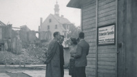 Fotoaufnahme der Baracke der Schweizer Hilfe auf dem Platz am Staatstheater vor der Trümmerlandschaft der Stadt. Im Hintergrund die Turmspitze der evangelischen Kirche. Fotoaufnahme der Baracke der Schweizer Hilfe auf dem Platz am Staatstheater vor der Trümmerlandschaft der Stadt. Im Hintergrund die Turmspitze der evangelischen Kirche.