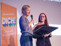 zwei Frauen sprechen, eine hält ein Mikrofon
