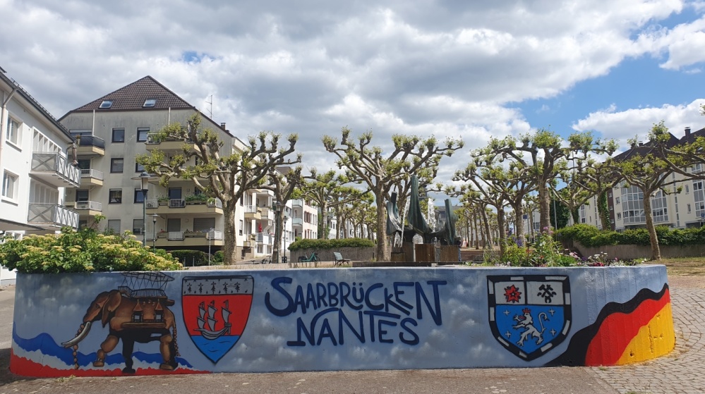 Mauer "Saarbrücken-Nantes" am Nanteser Platz Eine Mauer bemalt mit dem Elefanten aus Nantes, den Stadtwappen Nantes-Saarbrücken und dem Schriftzug "Saarbrücken-Nantes"