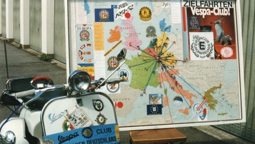 Geschmückte Vespa des Vespa-Clubs mit einer Landkarte im Hintergrund.