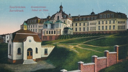 Die kolorierte Ansichtskarte aus den 1920er Jahren zeigt die Nordseite des Bürgerhospitals mit dem Pavillon der Leichenhalle. 