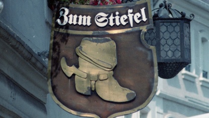 Schild mit der Beschriftung "Zum Stiefel" und einem abgebildeten Stiefel an dem Gebäude des Gasthauses.
